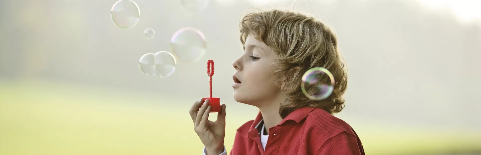 Ett barn blåser såpbubblor utomhus. Foto.